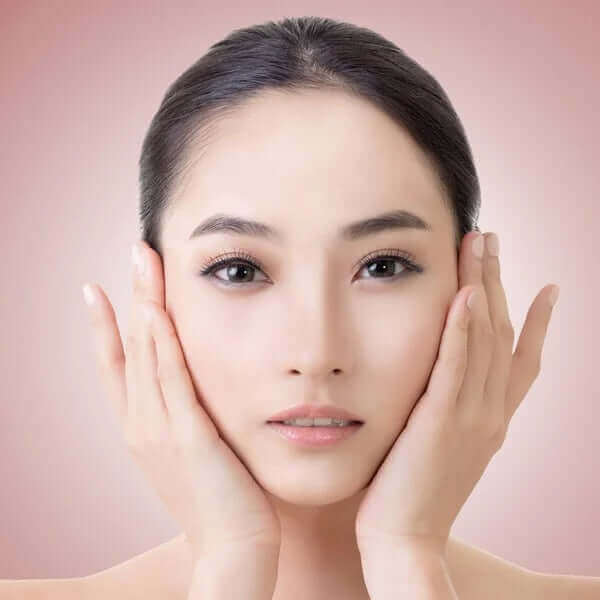 Woman gently holding her face, showcasing a healthy and radiant complexion, symbolizing K-beauty skincare.