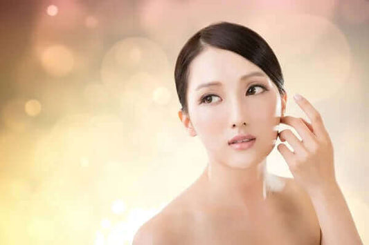 Young woman with flawless skin showcasing Korean beauty routine against a soft bokeh background.