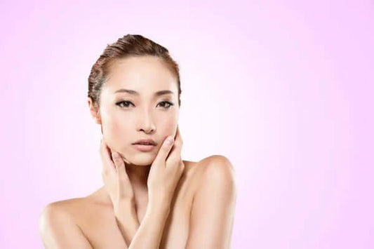 Woman with radiant skin, showcasing a natural skincare routine against a pink background.