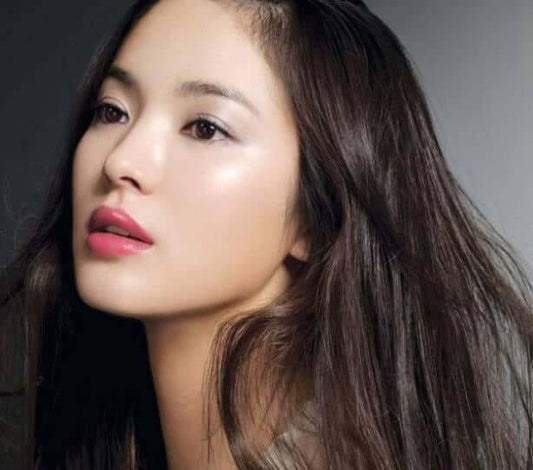 Stylish woman with radiant skin featuring long dark hair and bold pink lips, exemplifying beauty.