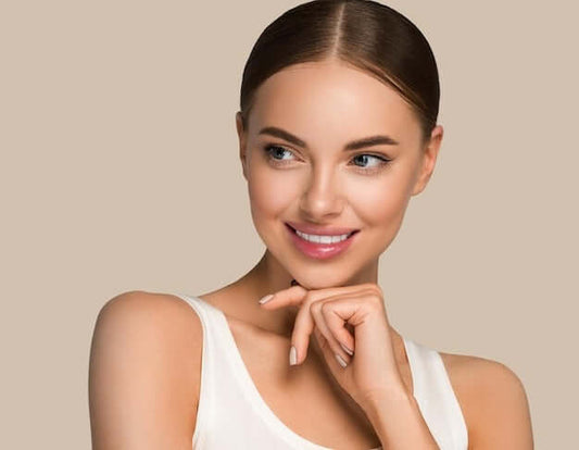 Smiling woman showcasing glowing skin, emphasizing the benefits of a travel skincare kit.