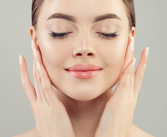 Close-up of a woman gently applying skincare, showcasing glowing skin and a serene expression.