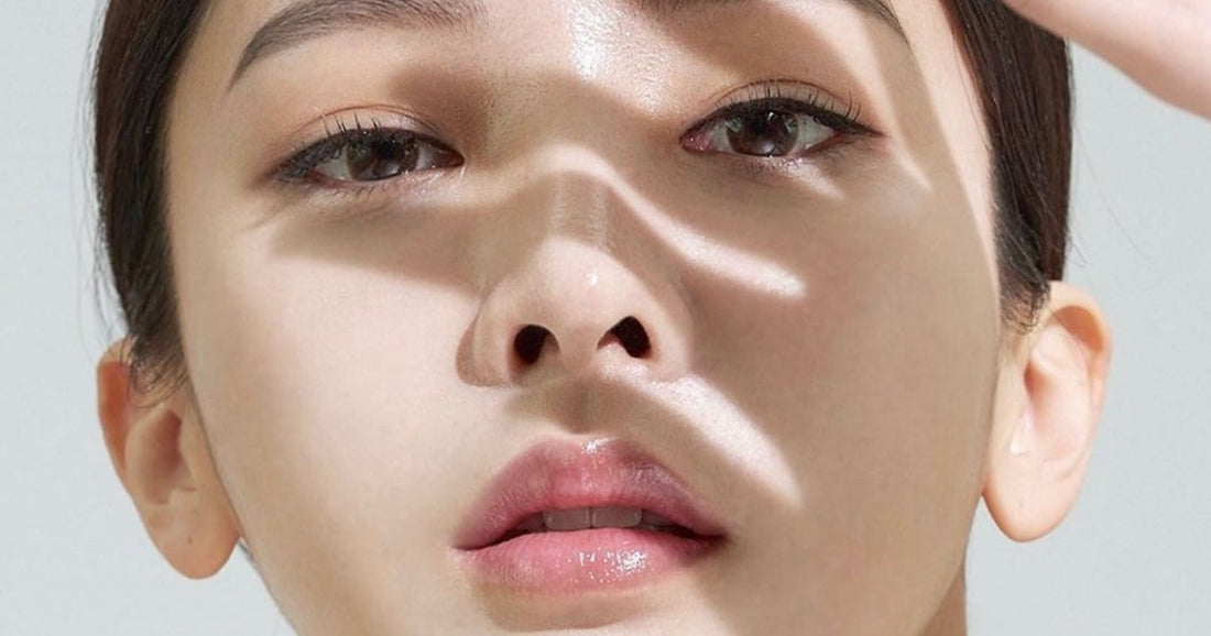 Close-up of a woman's face with radiant skin, illuminated by soft light and shadows highlighting her features.