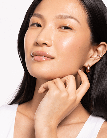 Close-up of a woman showcasing glowing skin and elegant earrings, highlighting a radiant beauty look.