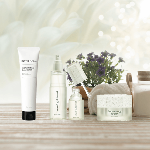Close-up of Riman ICD Mini Ritual Set - Snow Enzyme Cleanser, Dermatology First Package booster and serum bottles and Dermatology Cream with natural lighting and green accents