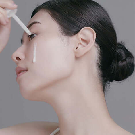 Woman applying RADIANSOME 100 Microfluidizer Ampoule for hydration and anti-aging benefits.