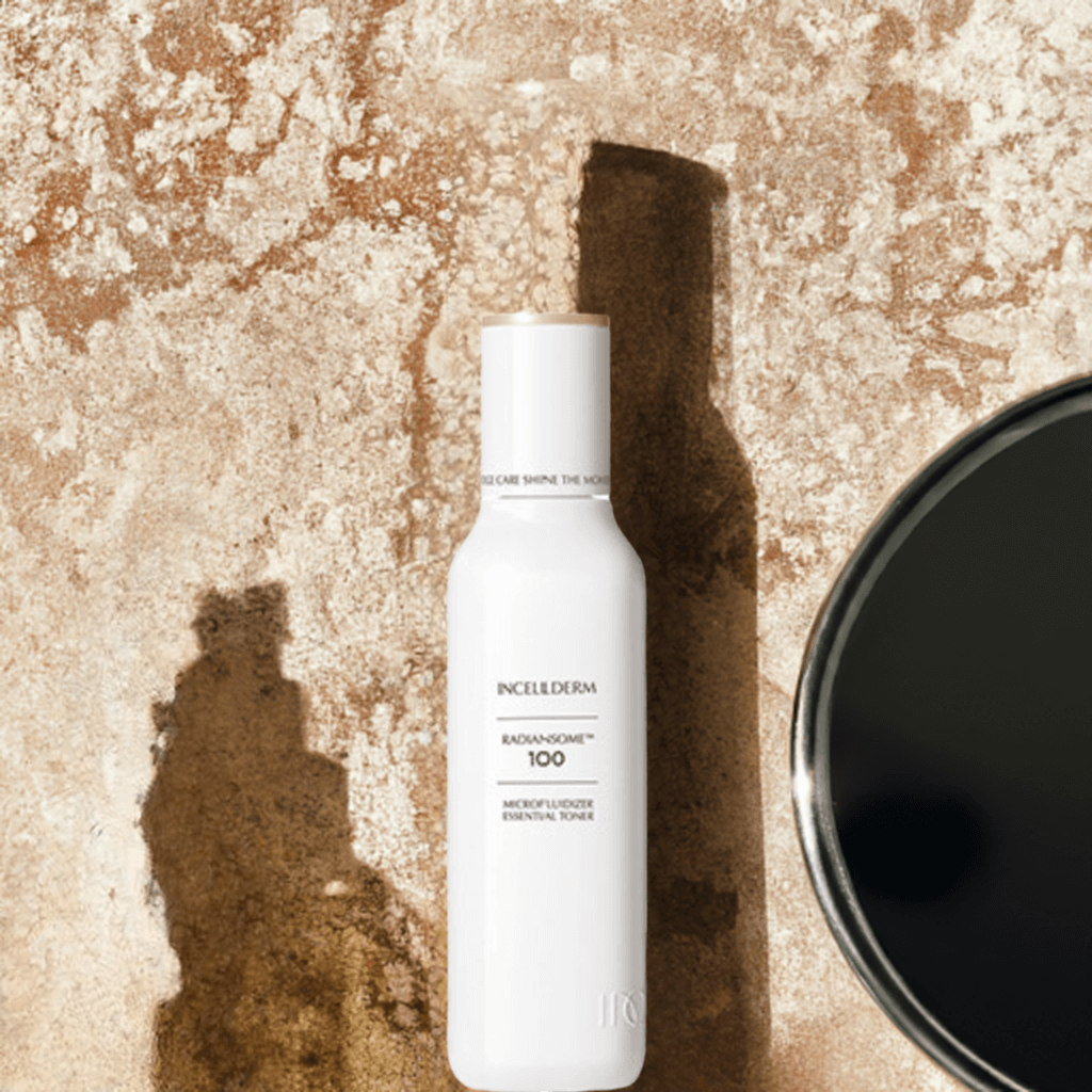 RADIANSOME 100 Microfluidizer Essential Toner bottle on textured surface, showcasing advanced anti-aging skincare.