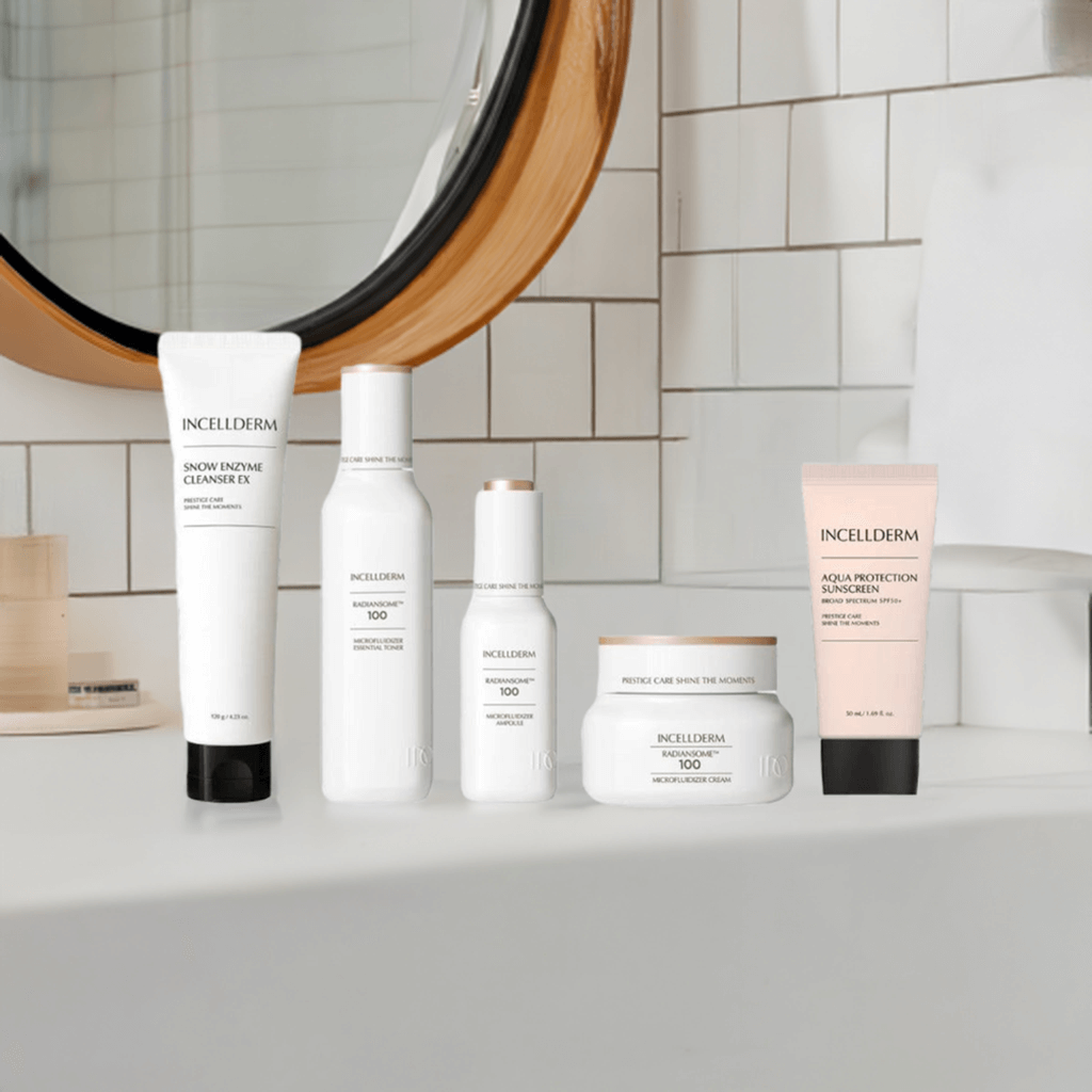 Five-piece skincare set by Incellderm on a bathroom counter, including cleanser, essence, and sunscreen.
