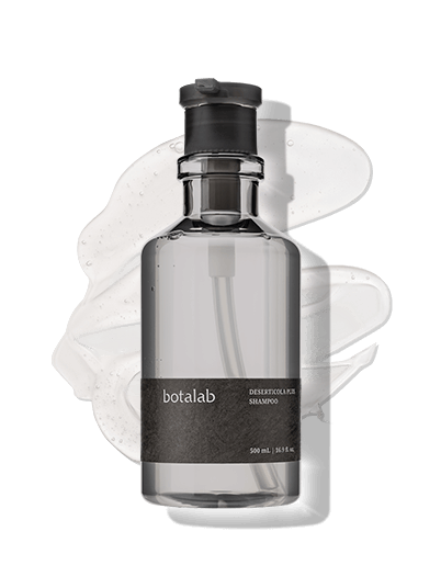 Front-facing view of Deserticola Plus Shampoo with pump dispenser and botanical background – Botalab hair treatment