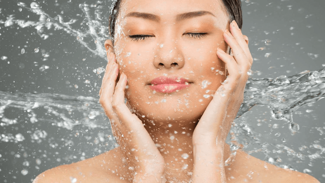 Woman enjoying a refreshing cleanse with water splashing around her face, showcasing hydration and skincare.