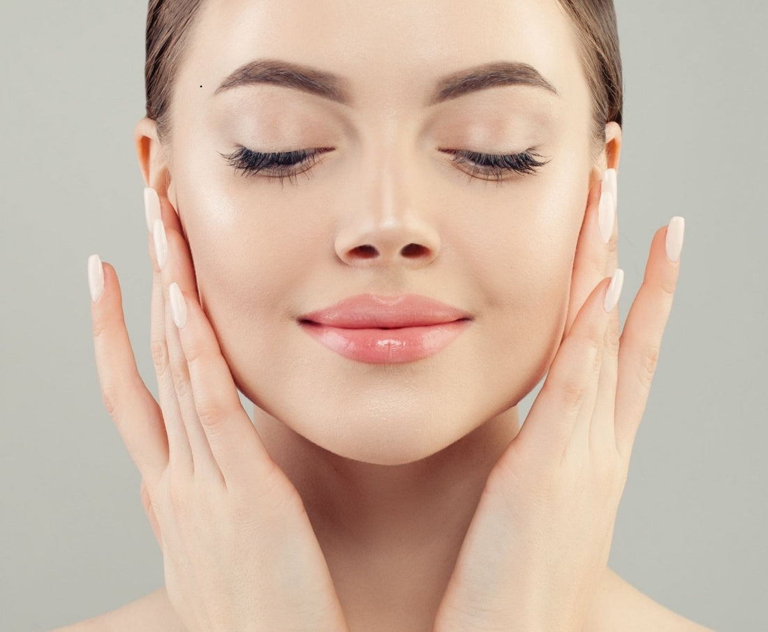 Close-up of a woman gently applying skincare, showcasing glowing skin and a serene expression.